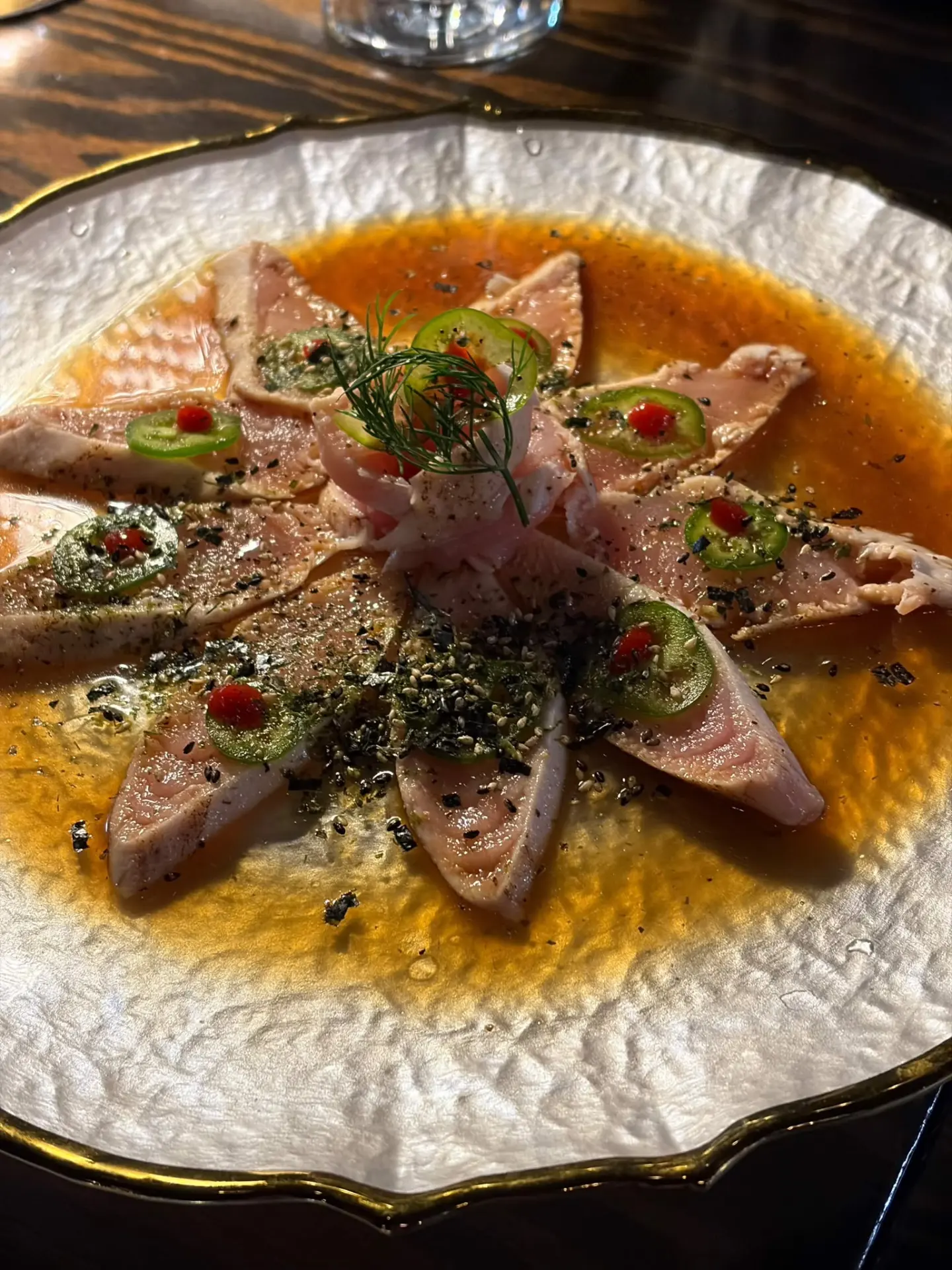 Tuna sashimi with jalapeño and dill arranged in a star on a pearl plate