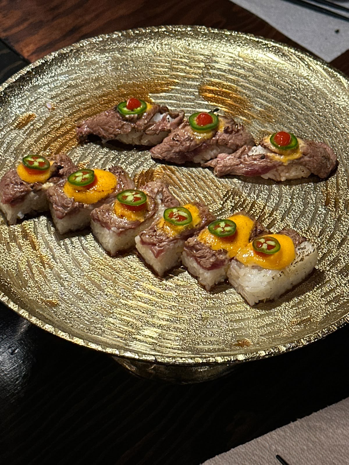 Sliced tasting dish with colourful garnishes on a gold plate