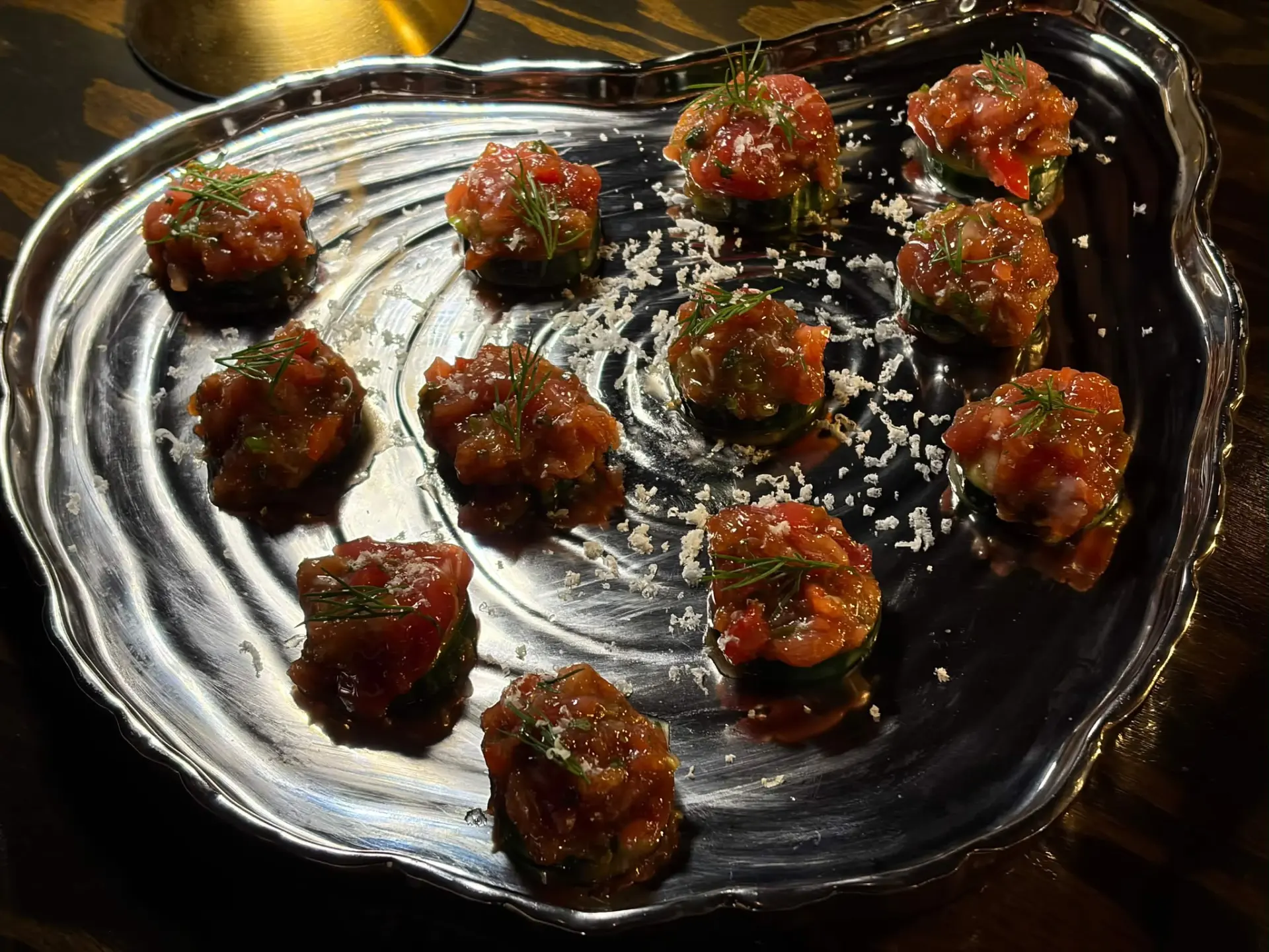 Spicy tuna tartare bites on cucumber rounds on a silver tray