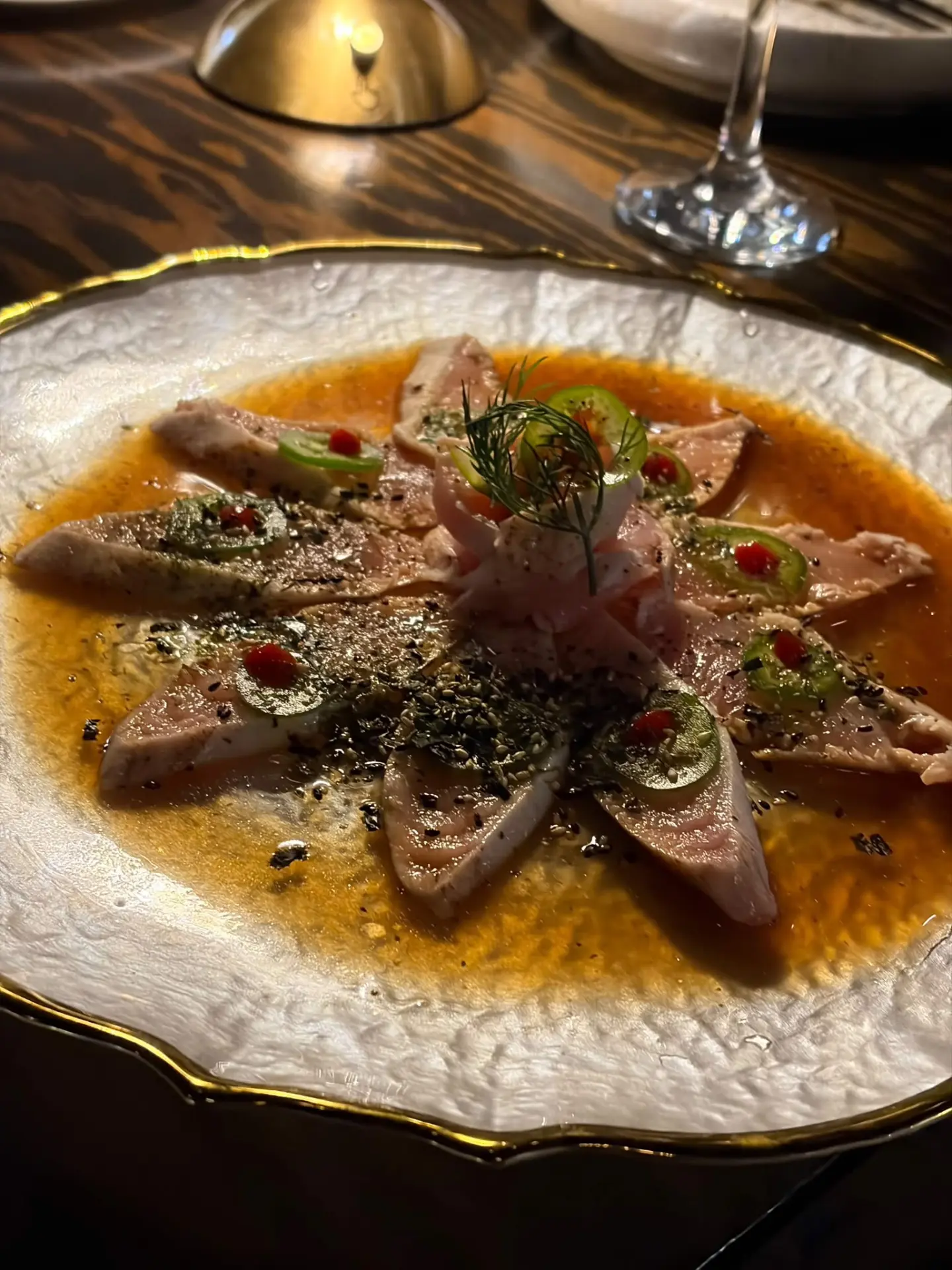 Tuna sashimi beside a wine glass in warm evening light