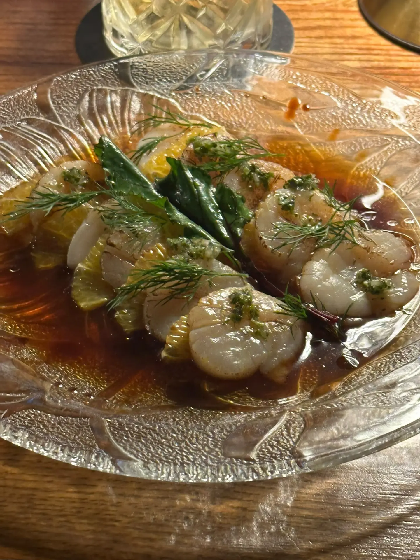 Scallops with citrus and fresh herbs on a textured glass plate