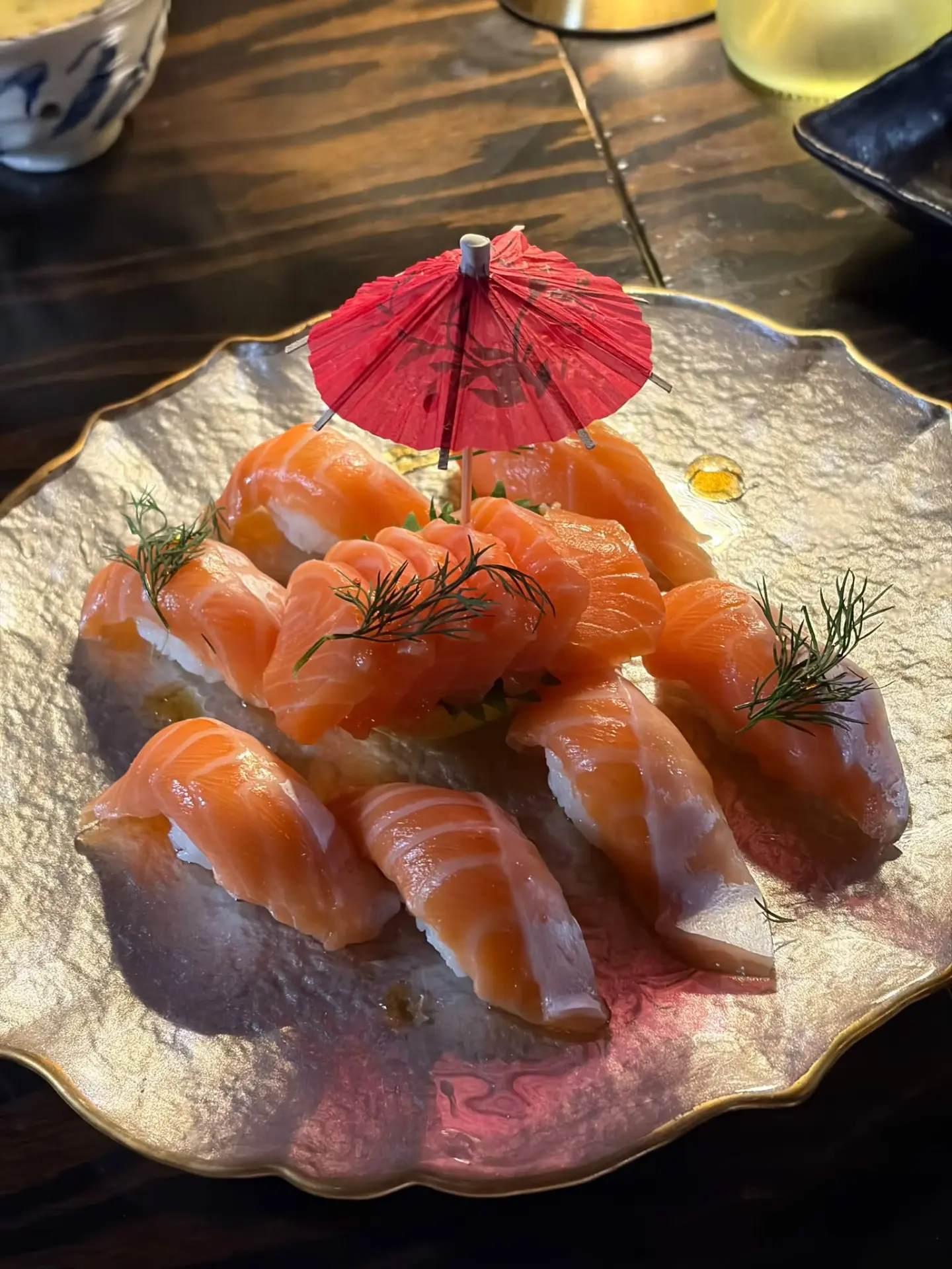Salmon nigiri garnished with dill and a cocktail umbrella