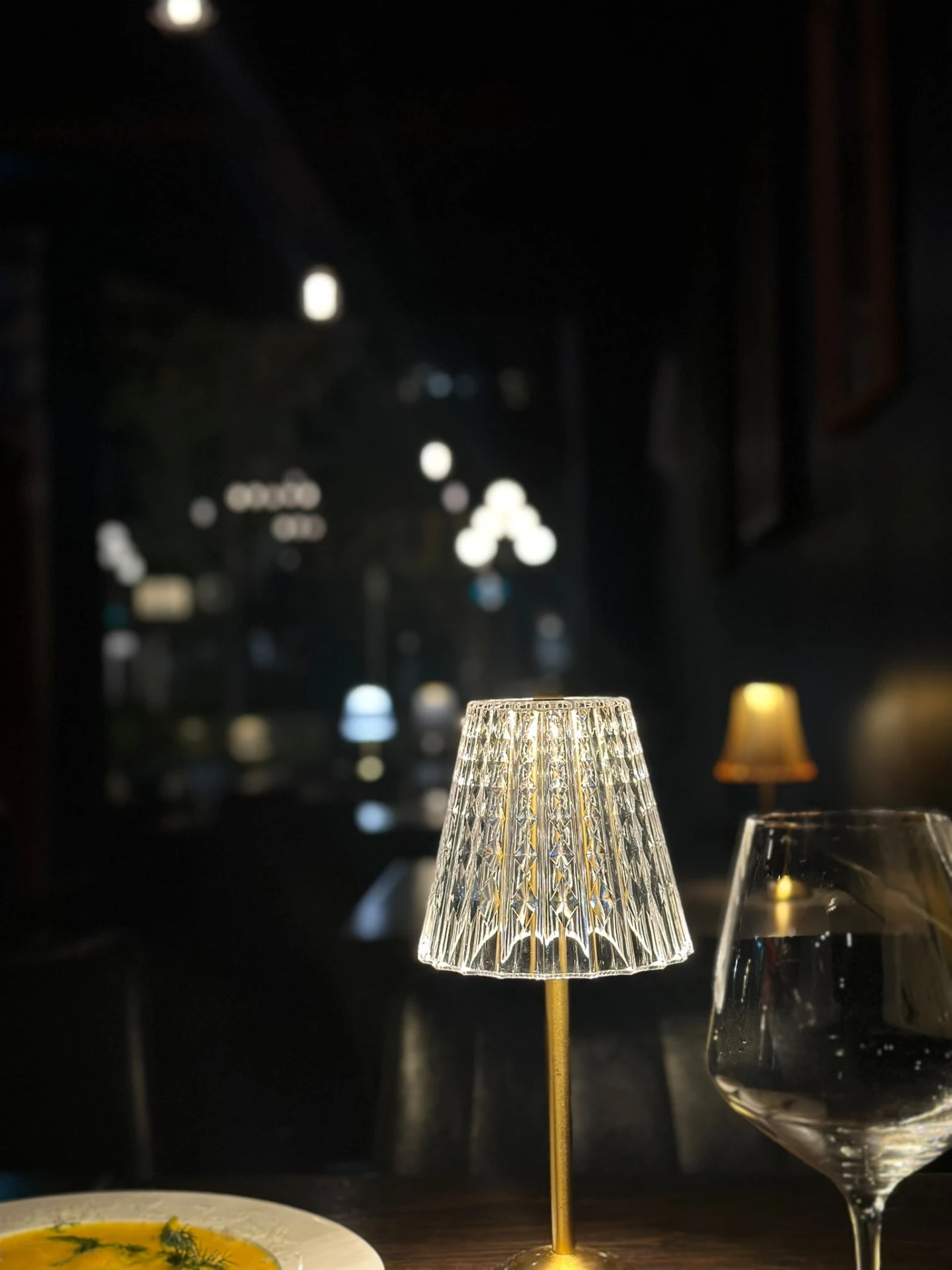 A glowing crystal table lamp and wine glass in the Muse dining room