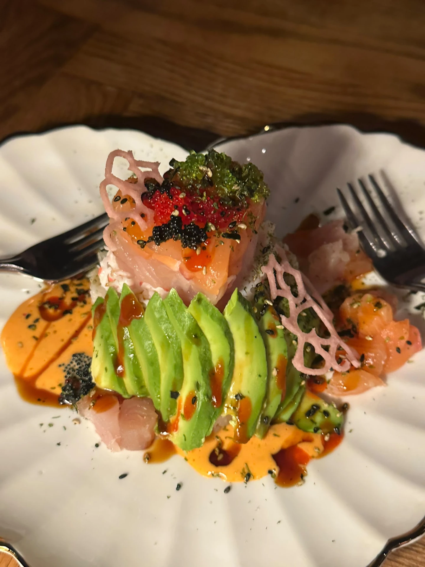 Sashimi and sliced avocado with colourful roe on a white plate